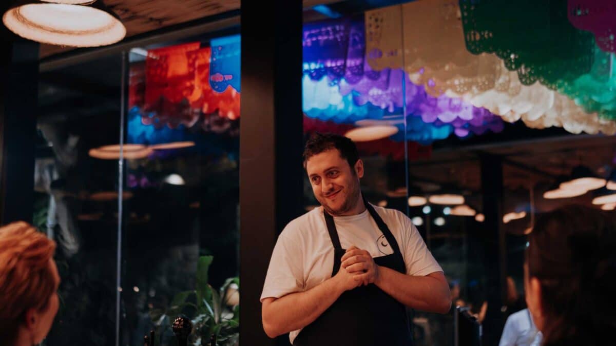 a man in a white apron standing in a restaurant