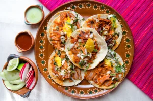 El origen de los tacos al pastor es una historia de migración, fusión cultural y creatividad mexicana. Este platillo se convirtió en uno de los grandes símbolos de la gastronomía mexicana. Descubre cómo nació, por qué se sirve en trompo y cómo conquistó al mundo.