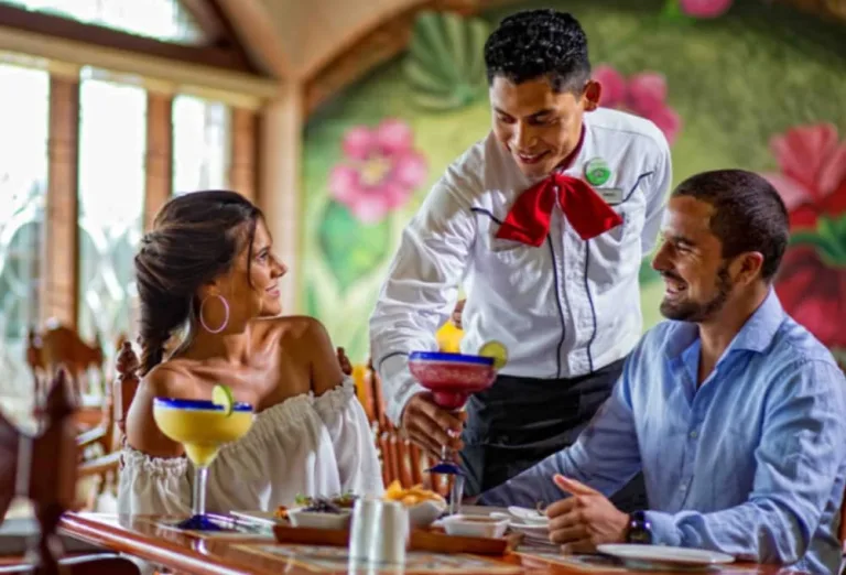 Meseros atienden a turistas en restaurante.