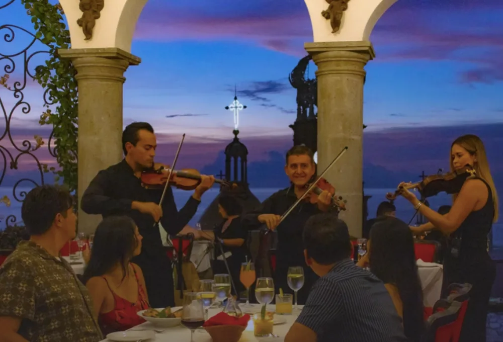 La Cappella Restaurant: Por qué el “spot” más viral de TikTok en Puerto Vallarta. Comensales cenando mientras violinistas ejecutan clásicos.